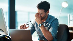 Frustrated man holding his face as he deals with mental health challenges at work